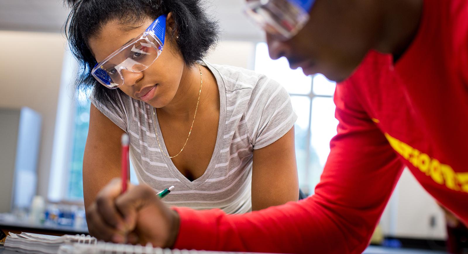 图为两名波胆网站的学生戴着护目镜在化学实验室工作.
